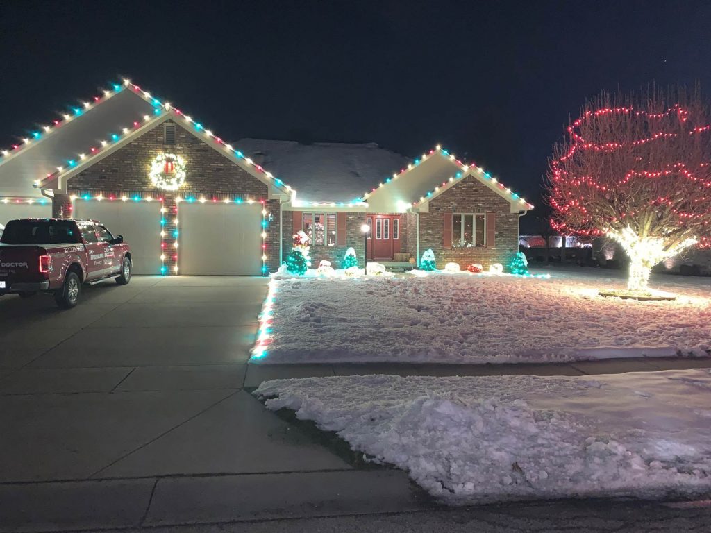 brick house with Christmas lights and snow
