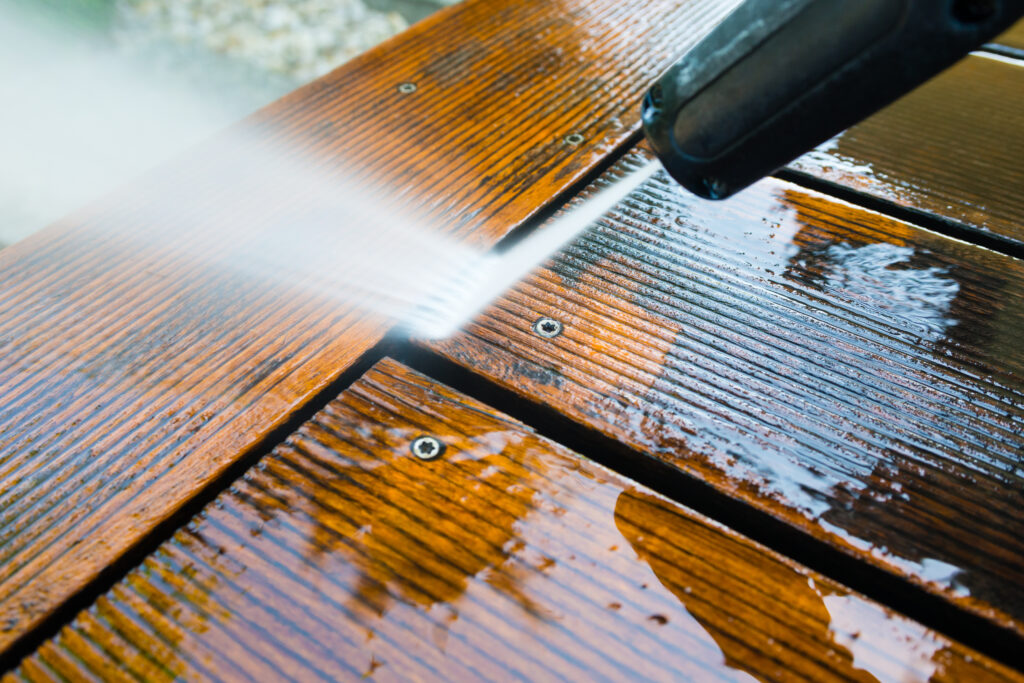 cleaning terrace with a power washer - high water pressure cleaner on wooden terrace surface. Preventing Wood Rot on Your Property